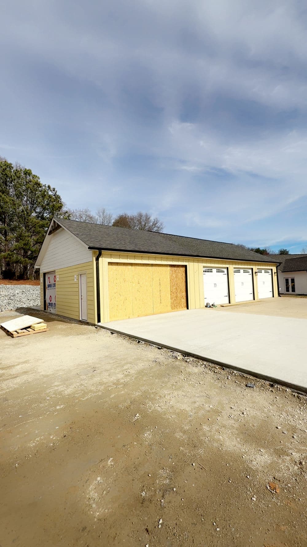 Newly constructed storage facility with wooden doors and unfinished concrete slab.