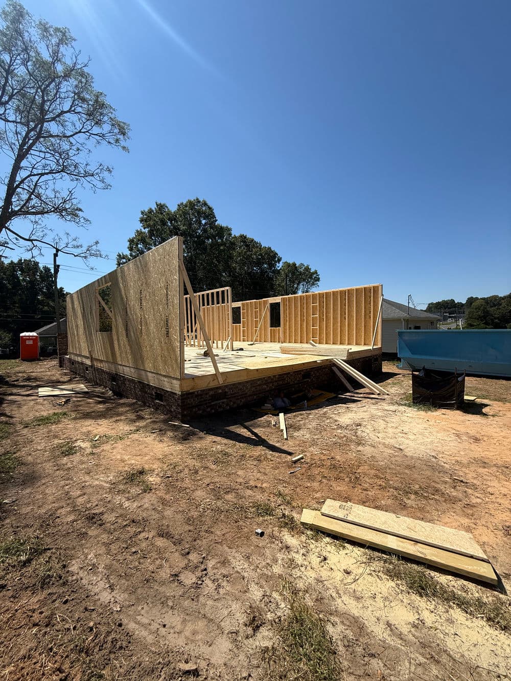 Construction site with wooden framing for a new building under clear blue sky.