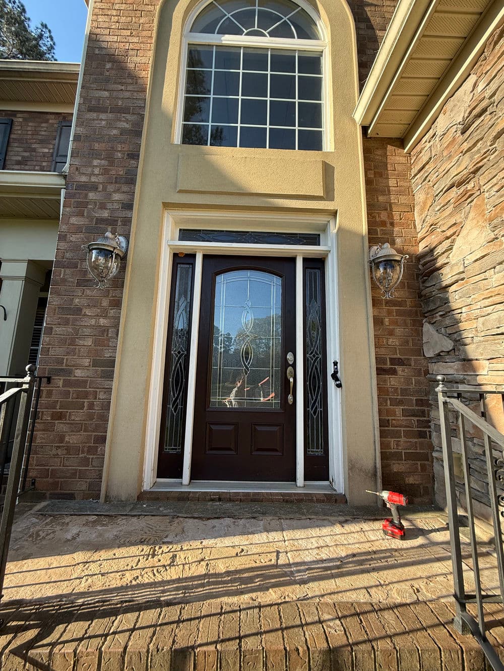 Elegant front entrance of a brick home with decorative glass door and sidelights.