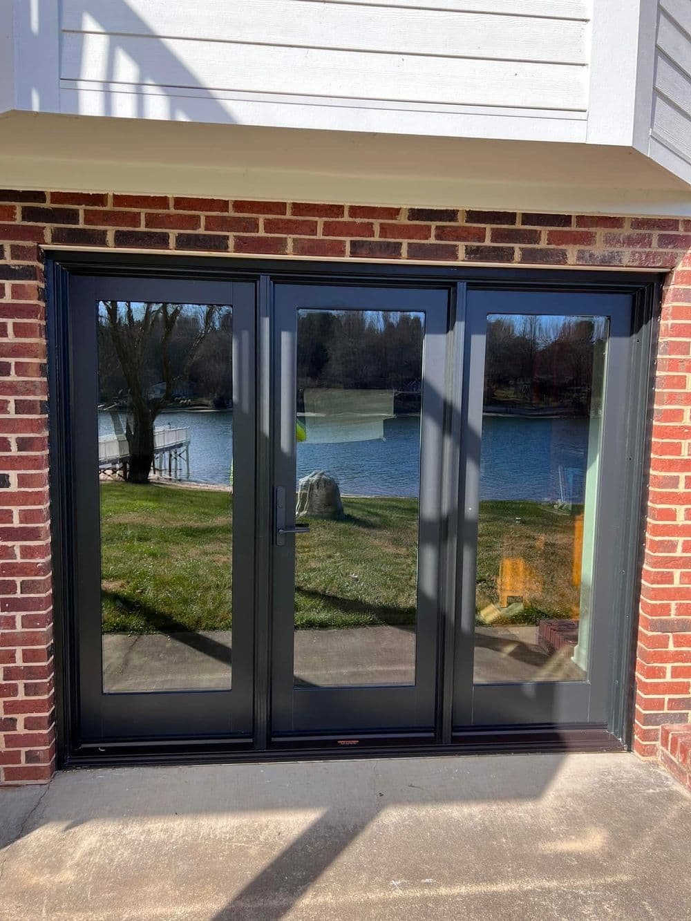 Modern black sliding doors with large glass panels overlooking a serene lake.