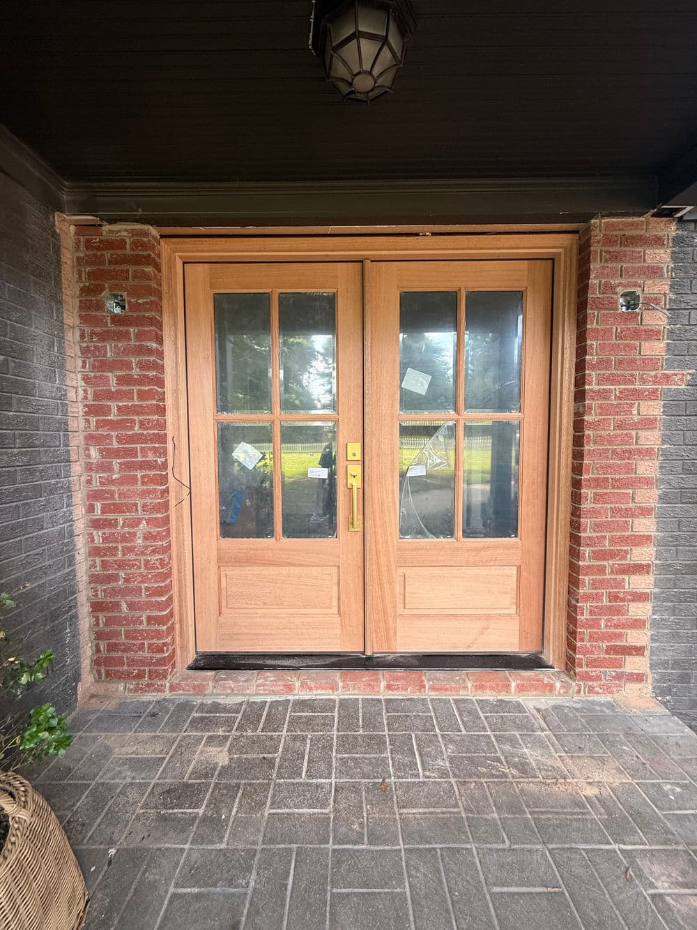 Wooden double doors with glass panels, framed by brick walls and a stone walkway.