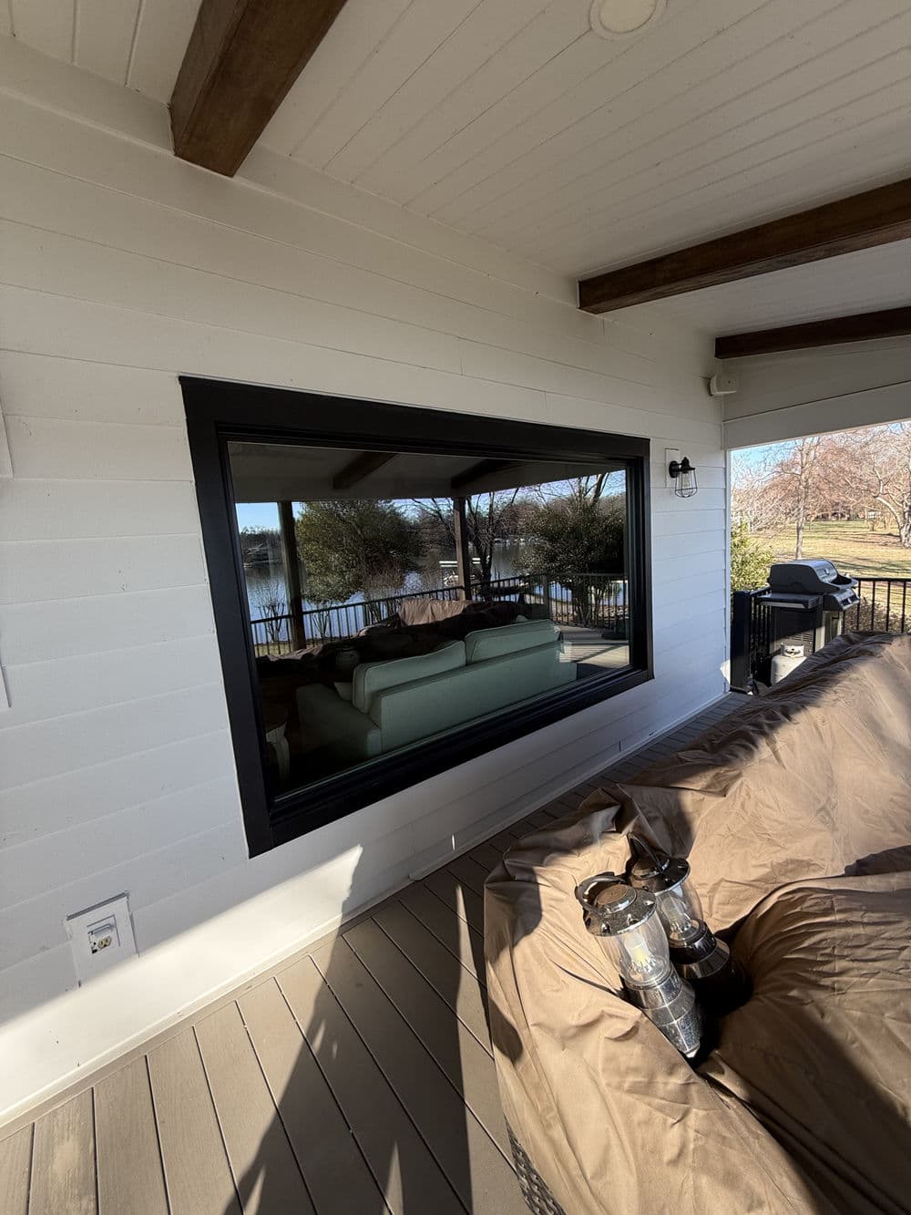 Modern black-framed window overlooking a scenic outdoor view with a cozy sofa inside.