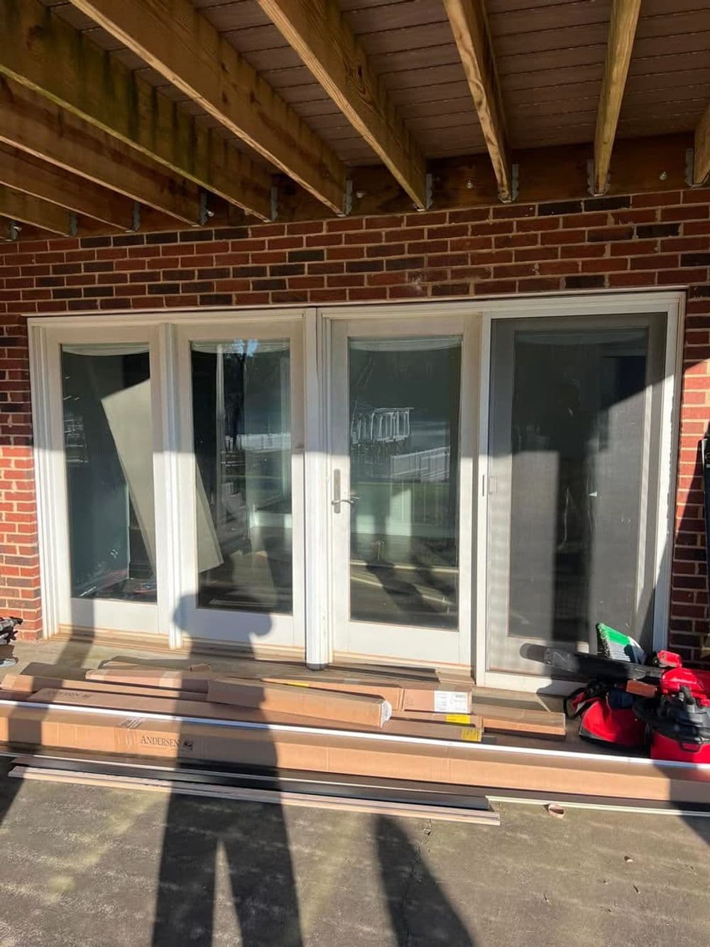 Sliding glass patio doors under construction with brick wall and materials nearby.