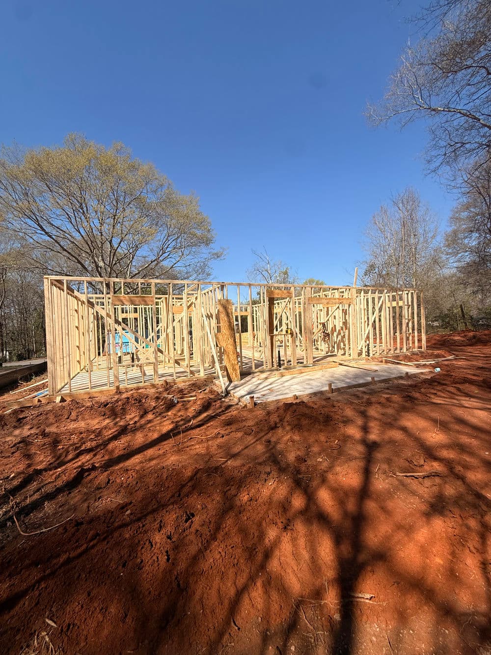 Construction site with wooden framing against a clear blue sky and red soil.